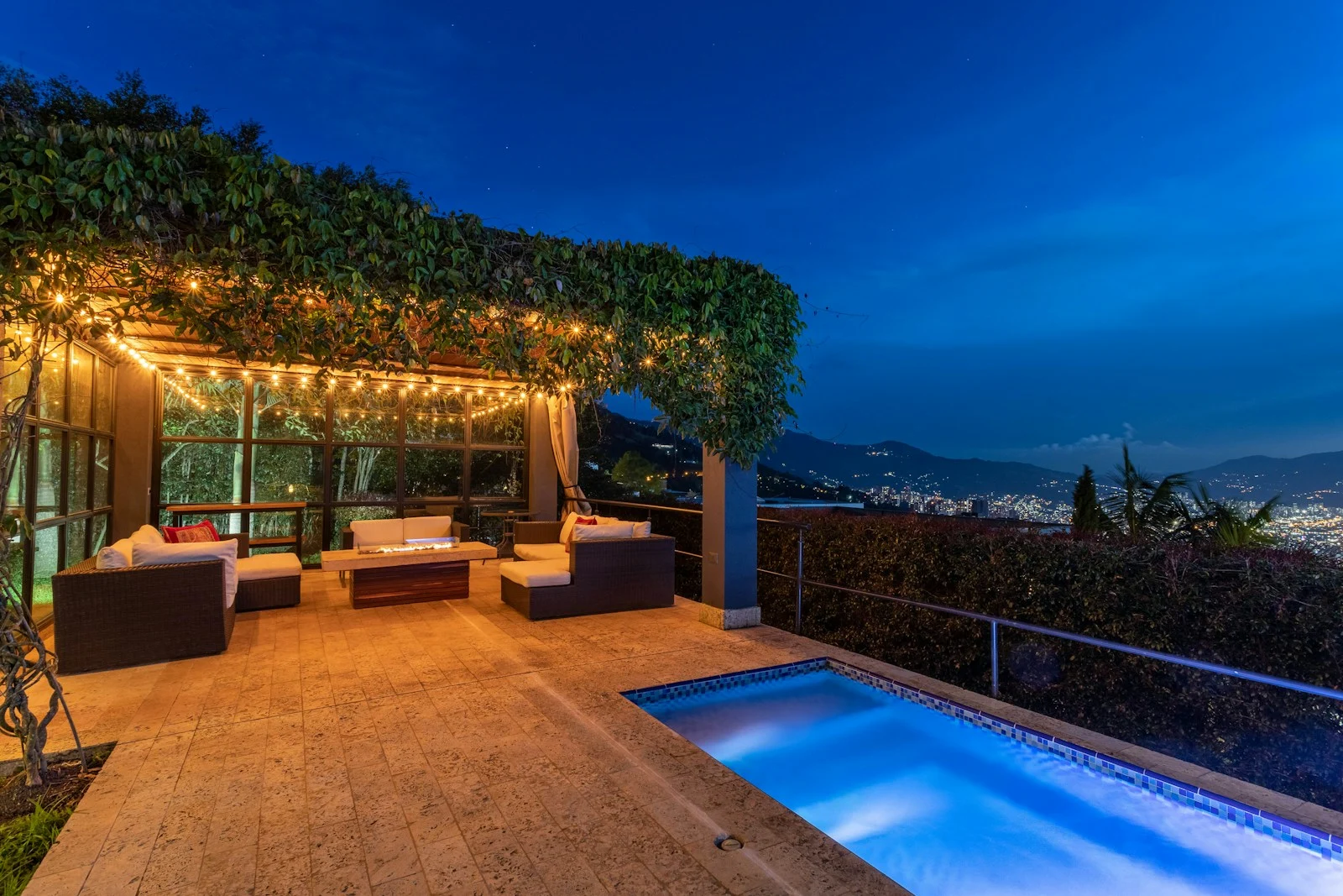 Evening patio with string lights, comfortable seating, and a blue swimming pool