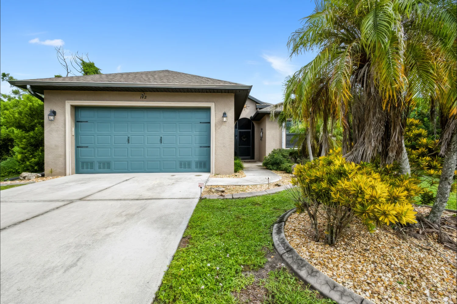 Palm-lined driveway and two-car garage