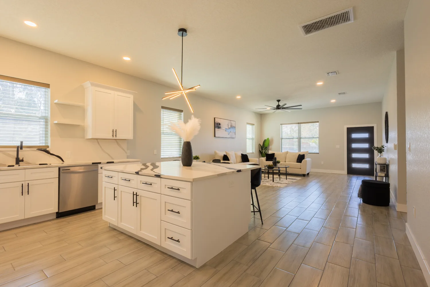 Open kitchen with a white island and adjoining living area